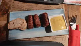Mici e pane: un assaggio di cosa mangiare a Bucarest. Salsicce grigliate servite con pane fresco e senape.