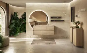 Une **salle de bain chic et cosy** avec un meuble vasque en bois clair, un grand miroir rond lumineux, des plantes luxuriantes et une ambiance apaisante.