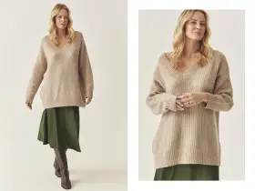 Modelka w beżowym swetrze w stylu oversize i zielonej spódnicy.