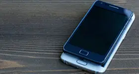 Dwa smartfony leżą na drewnianym blacie. Jeden, ciemny, spoczywa na drugim, srebrnym. Chciałbym skopiować moje urządzenie.