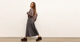 Modelka w luźnej, szarej spódnicy i brązowej bluzce. Idealny zestaw, który pokazuje, co pasuje do szarej bluzki.