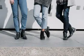Trzy pary damskich jeansów i różne buty: botki na obcasie, zamszowe botki i eleganckie botki. Idealne inspiracje, jakie buty do jeansów damskich wybrać.