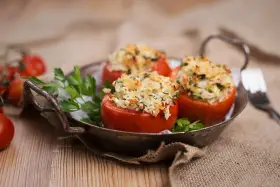 Pomodori ripieni di riso freddi, un piatto estivo gustoso e leggero, serviti in un vassoio rustico con prezzemolo fresco.