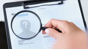 Dłoń z lupą bada CV, szukając idealnego kandydata. Techvisie Deventer w akcji!