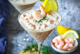Ein cremiger Shrimp Cocktail in einem Martiniglas, garniert mit Dill und Zitrone. Ein köstlicher Genuss!