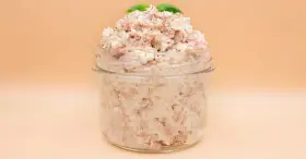 Pyszna pasta z tuńczyka i twarogu, doprawiona pieprzem, w słoiku, ozdobiona listkami bazylii. Idealna na kanapki.