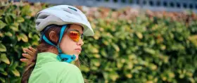 Młoda rowerzystka w kasku i okularach przeciwsłonecznych. Czy kask na rower jest obowiązkowy? Bezpieczeństwo przede wszystkim!