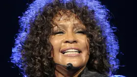 Whitney Houston z zamkniętymi oczami, w pełni emocji, pokazuje niesamowitą **skalę głosu**.
