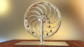 Glänzendes Rad mit schwarzen Kugeln, das an ein Perpetuum mobile erinnert, steht auf einem Holztisch.
