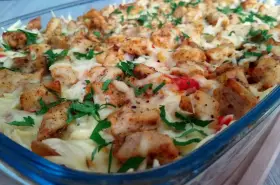 Pyszna zapiekanka gyros z makaronem, posypana serem i natką pietruszki, w szklanym naczyniu.