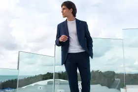 Uomo con tailleur blu a quadri, maglione bianco. Perfetto per capire con che scarpe abbinare.