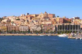 Vista del quartiere Marina di Cagliari con palazzi colorati, palme e yacht ormeggiati.