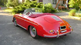 Czerwony kabriolet Porsche 356 z lat 50. stoi na podjeździe, gotowy na letnią przejażdżkę.