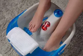 Pieds dans un bain à bulles, profitant d'un moment de détente pour la beauté des pieds. Une serviette blanche est à portée de main.