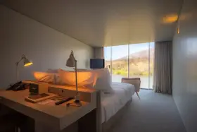 Un angolo studio in camera da letto con vista sul lago. Due lampade illuminano la scrivania con telefono e altoparlante.