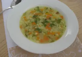 Pyszna ryżanka z marchewką i natką pietruszki, podana w białej miseczce, gotowa do jedzenia.