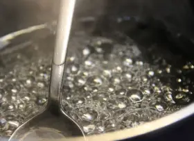 Gotowy syrop cukrowy w trakcie gotowania. Bąbelki unoszą się na powierzchni, a łyżka sprawdza konsystencję. Idealny przepis na domowy syrop.