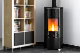 Stufa a pellet moderna con fiamma viva, ideale per dormire con la stufa a pellet accesa in un ambiente accogliente, accanto a una libreria.