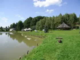 Malownicze dzikie łowiska Małopolska: spokojna woda, zielone wzgórza, drewniana altana i miejsca do wypoczynku.