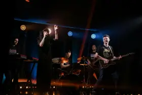 Zespół rockowy na scenie: wokalistka, gitarzysta, basista, perkusista i klawiszowiec. Koncert jak z listy zespoły rockowe zagraniczne alfabetycznie.