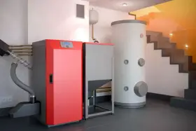 Instalación moderna para cambiar caldera de gas por pellets. Caldera roja, depósito de pellets y acumulador de agua.