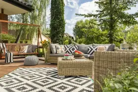 Relaks na tarasie w stylu boho: wiklinowe meble, huśtawka, wzorzysty dywan i mnóstwo zieleni.