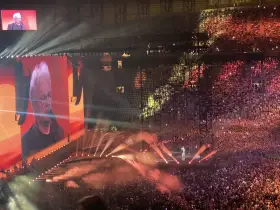 Koncertowa noc z piosenkarką sanah. Ogromna publiczność, światła i ekran z wizerunkiem artystki.