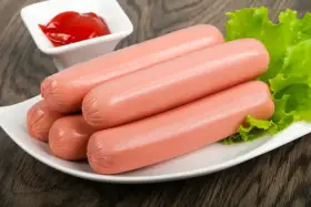 Kilka parówek na talerzu z sałatą i ketchupem. Idealne do szybkiego obiadu, dowiedz się, jak ugotować parówki.