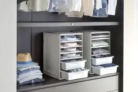 Organizzazione armadio: camicie piegate in contenitori modulari, pile di vestiti e un cappello su una mensola.