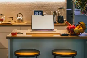 Ein Laptop steht auf einer Küchentheke neben Obst und einem Glas Tee. Vielleicht fragst du dich, was Bixby ist – ein digitaler Assistent, der dir bei vielen Dingen helfen kann.