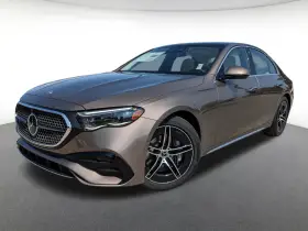 Elegancki brązowy Mercedes-Benz E450 sedan z czarnymi felgami stoi na szarym podłożu.