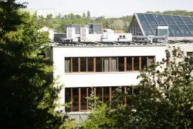 Nowe budynki od września 2026 będą musiały posiadać instalację fotowoltaiczną. Na dachu budynku widać panele i klimatyzatory.
