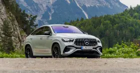 Biały Mercedes GLE 53 AMG coupe na tle górskiego krajobrazu z lasem.