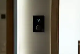 Nowoczesny panel sterowania ogrzewaniem domu pokazuje 27 stopni.