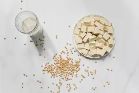 Tofu en cubos, leche de soja y semillas de soja. La nattokinase que es, se deriva de la soja fermentada.