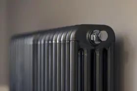 Gros plan sur un radiateur bain d'huile noir, avec un bouchon chromé visible. Un élément clé pour gérer la consommation d'énergie.