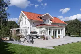 Vitt hus med rött tak och stor altan. Perfekt för att behandla altan och njuta av sommaren.