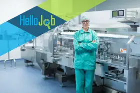 Pracownik w czepku i zielonym uniformie stoi przed linią produkcyjną. Szukasz pracy? Sprawdź cervo oferty pracy!