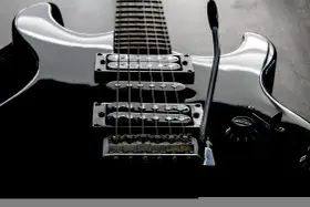 Czarna gitara elektryczna z sześcioma strunami, gotowa do rockowych riffów.