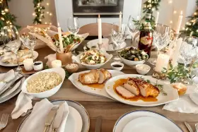 Mesa de Nochevieja con carnes asadas, ensaladas, velas y luces festivas.