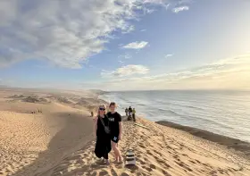 Dwie kobiety na wydmach nad oceanem, w tle inni turyści. Czy w Maroko jest bezpiecznie dla turystów? Tak, to piękny kraj.