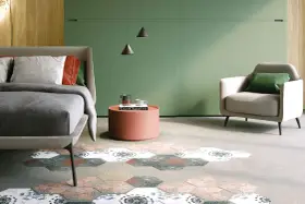 Camera da letto con pareti verde foresta, letto comodo, poltrona e un tappeto esagonale decorato.