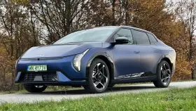 Niebieski Polestar 2 na tle jesiennych drzew. Elegancki samochód elektryczny z charakterystycznymi światłami i felgami.