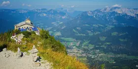 View from Hitler's Eagle's Nest, a stone building with blue umbrellas, perched high in the Bavarian Alps overlooking a valley.