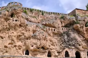 Antigua ciudad excavada en roca, con arcos y ventanas en las cuevas. Un lugar histórico que parece una cascada de piedra.