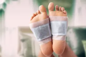 Close-up of feet with detox patches applied to the soles, demonstrating how to do a foot detox at home.