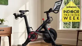 A Peloton bike, perfect for indoor cycling vs spinning, sits in a bright room. A yellow graphic promotes "Indoor Training Week.