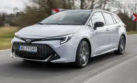 Srebrna Toyota Corolla 2.0 Hybrid w wersji kombi pędzi po drodze.