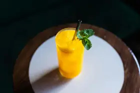 Orzeźwiający koktajl z mango, z lodem i listkami mięty, podany w szklance ze słomką.