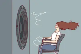 Une femme assise, les cheveux au vent, face à un haut-parleur. Le son est si fort qu'il en devient une force physique, illustrant la définition du décibel.